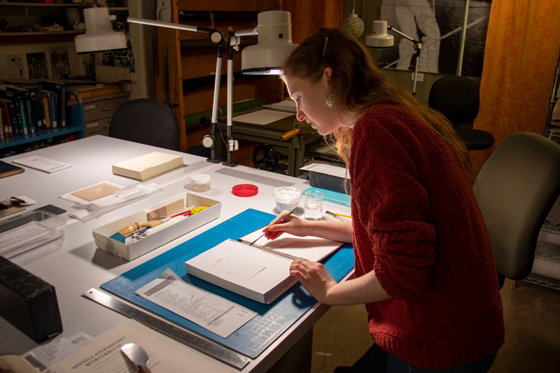 Woman working at desk on a book conservation project.