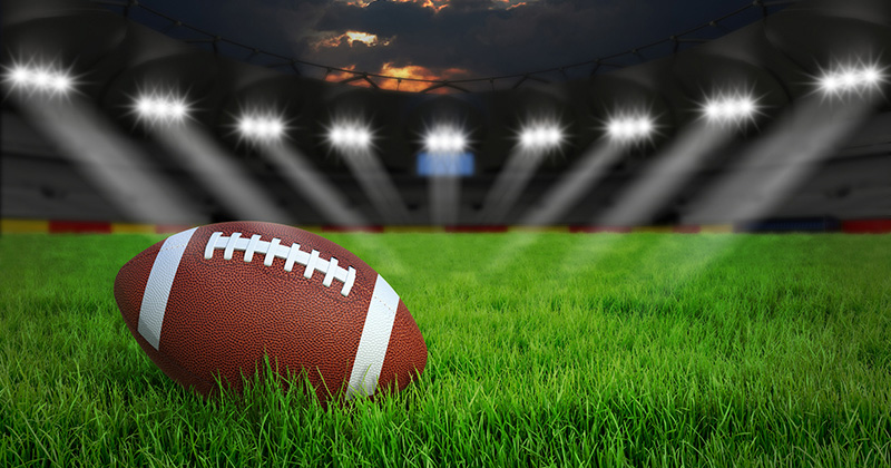 American football arena with ball on green grass illumination at night, 3D rendering