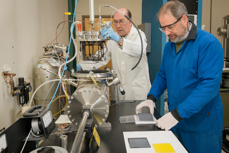 Brian McCandless (blue lab coat) is an associate scientist with the Institute of Energy Conversion (IEC) who's work focuses on "deposition and analysis of compound semiconductor thin films and devices photovoltaics" [IEC website]. In collaboration with Wayne A. Buchanan, research associate II at the IEC (white lab coat), he's been working on developing an improved vapor transport reactor deposition head design to allow for large-scale production of thin film photovoltaics. - (Evan Krape / University of Delaware)