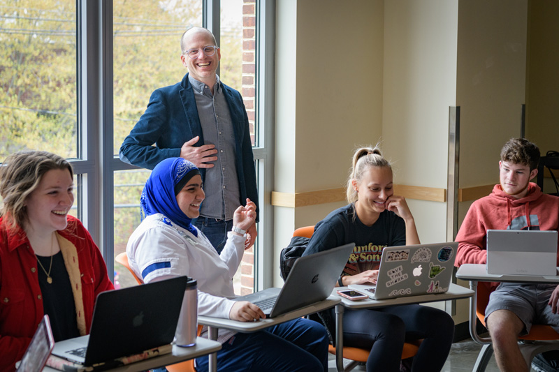 Assistant Professor Paul Jackson teaching a section of his GEOG 345: "Cultural Geography" class in which students were broken into two groups to play a "care or kill" turn-based role-playing game. The students in the class were divided into two groups - a "kill" group which tried to theoretically "kill" a fictionalized version of Prof. Jackson by changing his geographic location or demographic identify (age, nationality, gender, etc.) and a "care" group which would attempt to save him by modifying the same characteristics. The teams would role dice to determine the degree to which each would be permitted to change variables in the game. - (Evan Krape / University of Delaware)