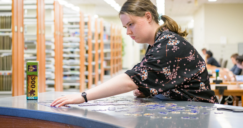 Puzzles at Morris Library at the Periodicals and Reference desk for students to put together when they need a break from their studying for finals. Photographed for a UDaily article about “de-stressing” during finals week. Pictured: Kate Whitcomb, a senior in the College of Arts and Sciences. - (Evan Krape / University of Delaware)