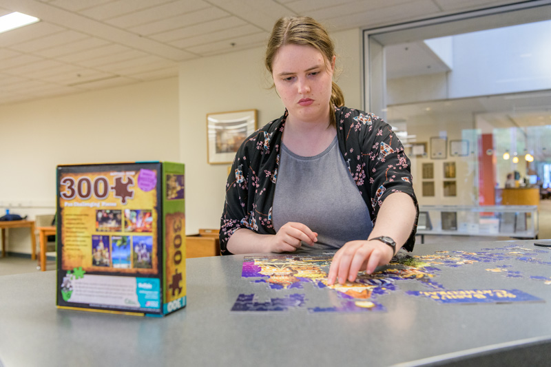Puzzles at Morris Library at the Periodicals and Reference desk for students to put together when they need a break from their studying for finals. Photographed for a UDaily article about “de-stressing” during finals week. Pictured: Kate Whitcomb, a senior in the College of Arts and Sciences. - (Evan Krape / University of Delaware)