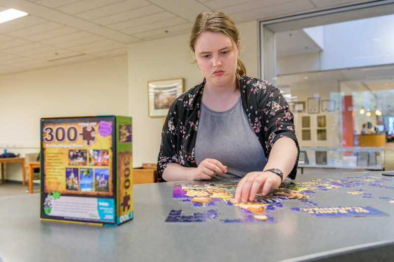 UDaily-Library_Puzzles-050819 Puzzles at Morris Library at the Periodicals and Reference desk for students to put together when they need a break from their studying for finals. Photographed for a UDaily article about “de-stressing” during finals week. Pictured: Kate Whitcomb, a senior in the College of Arts and Sciences. - (Evan Krape / University of Delaware)