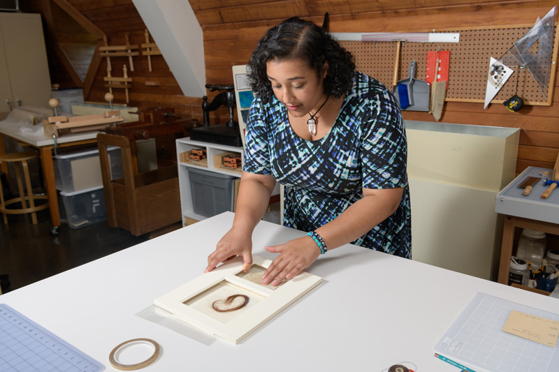 CAS-WUDPAC-Huff_Layla-Lizzie_Siddall_Hair-073019 Layla Huff (blue, white, black patterned dress) is an undergraduate student at Morgan State University who has been studying art conservation at Winterthur for an internship in the summer of 2019. Working with mentor Melissa Tedone, Huff has been preparing a lock of hair for exhibition in England. The hair comes from Elizabeth “Lizzie” Siddall, an English artist, poet, and artists' model. Until her husband, painter Dante Gabriel Rossetti, made her his exclusive model, Lizzie frequently modeled for drawing and paintings by the Pre-Raphaelite Brotherhood. The lock of hair comes from the Mark Samuels Lasner Collection (MSL Coll 6690) and was a "surprise" found among a collection of items purchased for the collection.