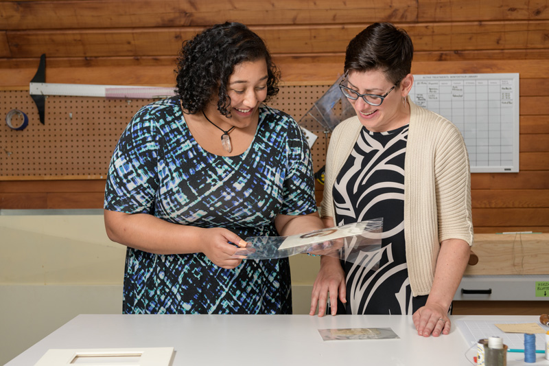 Layla Huff (blue, white, black patterned dress) is an undergraduate student at Morgan State University who has been studying art conservation at Winterthur for an internship in the summer of 2019. Working with mentor Melissa Tedone, Huff has been preparing a lock of hair for exhibition in England. The hair comes from Elizabeth “Lizzie” Siddall, an English artist, poet, and artists' model. Until her husband, painter Dante Gabriel Rossetti, made her his exclusive model, Lizzie frequently modeled for drawing and paintings by the Pre-Raphaelite Brotherhood. The lock of hair comes from the Mark Samuels Lasner Collection (MSL Coll 6690) and was a "surprise" found among a collection of items purchased for the collection.