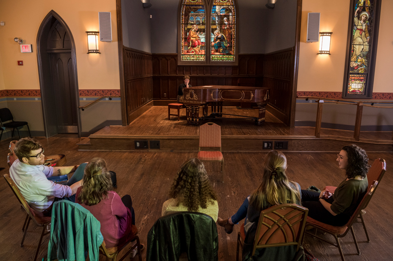 Mark Adams teaches a class in the Spring semester for students looking for more songwriting experience.  The class encourages participation and critiques to students such as Elizabeth Vex (tan sweater & curly hair), Allison Martin (long grey sweater/pinstrip shirt), Jamie Wechster (long maroon blouse), Emily Fareed (green sweater, brown hair), and Olivia Forney (black sweater “Dolly’s”). 