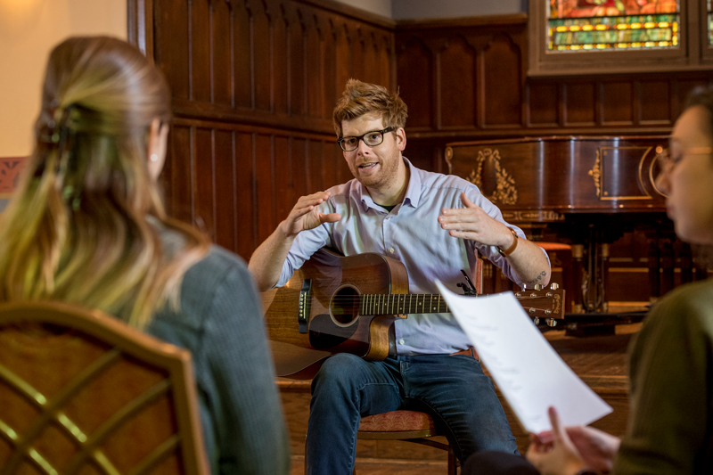 Mark Adams teaches a class in the Spring semester for students looking for more songwriting experience.  The class encourages participation and critiques to students such as Elizabeth Vex (tan sweater & curly hair), Allison Martin (long grey sweater/pinstrip shirt), Jamie Wechster (long maroon blouse), Emily Fareed (green sweater, brown hair), and Olivia Forney (black sweater “Dolly’s”). 