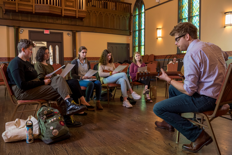 Mark Adams teaches a class in the Spring semester for students looking for more songwriting experience.  The class encourages participation and critiques to students such as Elizabeth Vex (tan sweater & curly hair), Allison Martin (long grey sweater/pinstrip shirt), Jamie Wechster (long maroon blouse), Emily Fareed (green sweater, brown hair), and Olivia Forney (black sweater “Dolly’s”). 