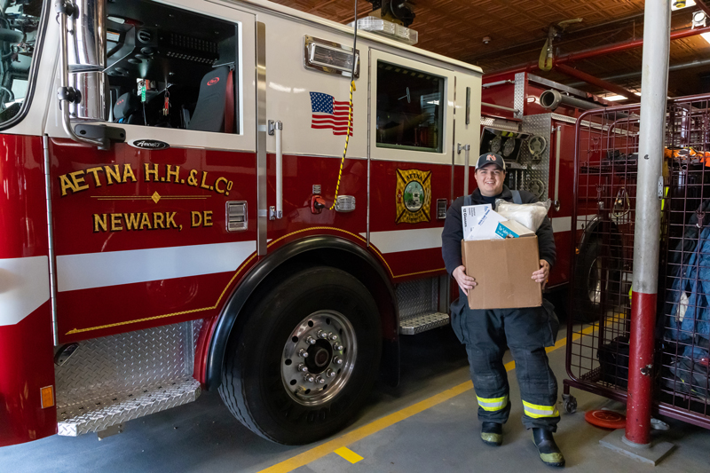 Firefighter Christian Bethard of Newark’s Aetna Hose, Hook and Ladder Co. holding medical supplies that were donated by the University of Delaware to help protect emergency responders during the COVID-19 pandemic.