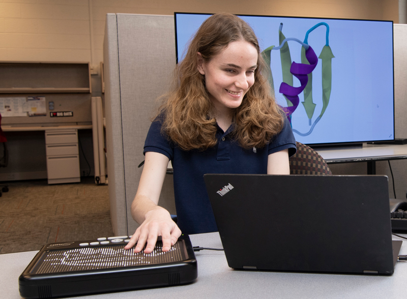 Olivia Shaw was an undergrad at another school and came to UD last summer to take part in the research experience program that Chem Prof. Karl Booksh has run at UD for several summers for students with disabilities. They usually return to their home schools in the fall, but Olivia, who I believe is legally blind, transferred here as a chem major. She's continued working in Prof. Jodi Hadden-Perilla's lab and is making significant contributions to her research. Her name MAY be one of the co-authors on an upcoming paper.  She works on a Graphiti device to help her interprete graphs and proteins in order to better do her research.