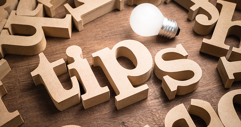 Tips wood word in scattered wood letters with glowing light bulb
