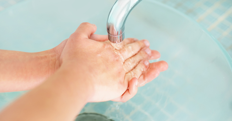 Cropped view of female washing hands in bathroom