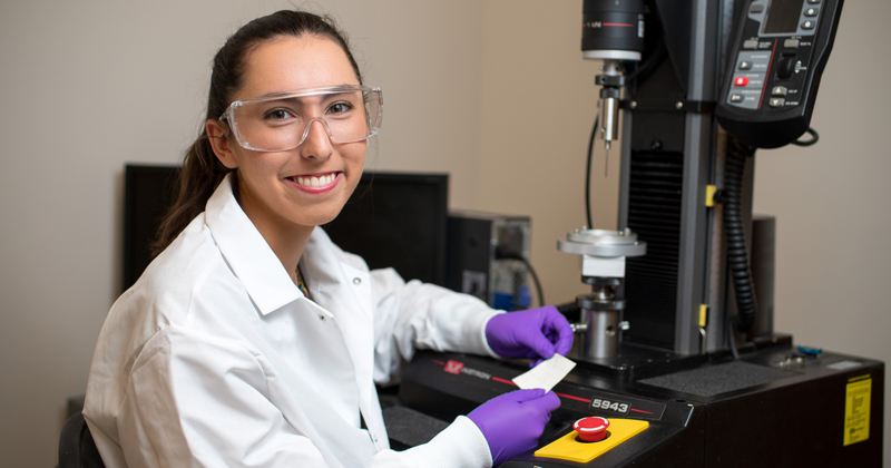 Undergraduate summer researcher, Erin Hogan, testing fabric for the International Space Station under the direction of Norm Wagner.