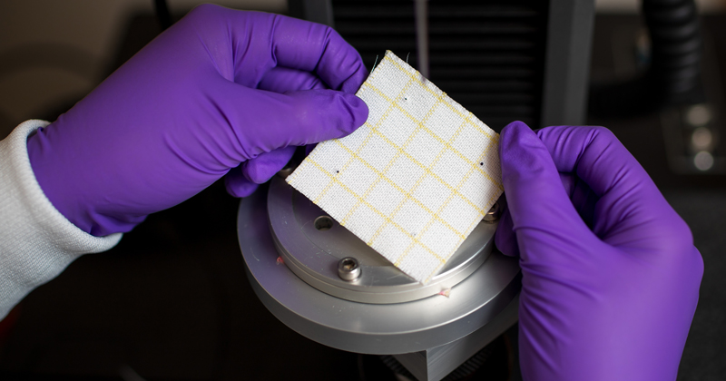 Undergraduate summer researcher, Erin Hogan, testing fabric for the International Space Station under the direction of Norm Wagner.