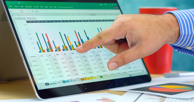 Hand pointing at Microsoft Excel bar chart on tablet