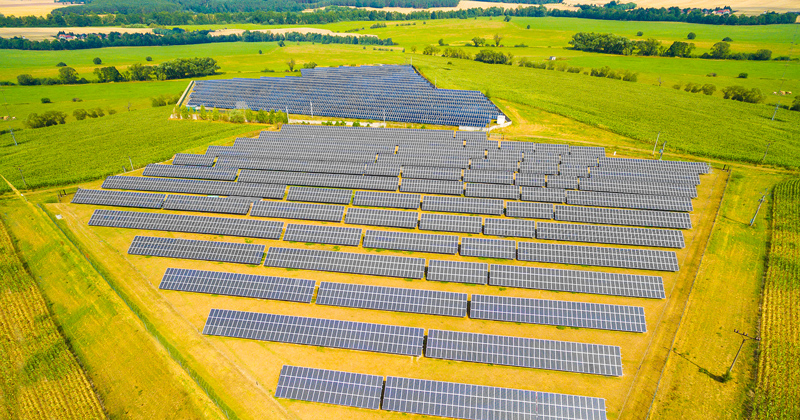 Aerial view to solar power plant in corn fields. Industrial background on renewable resources theme.