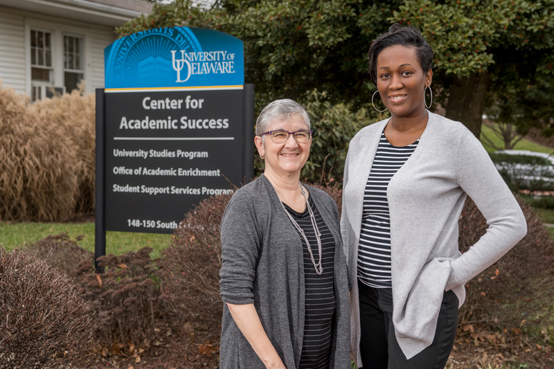 Office of Academic Enrichment - Lysbet Murray & Corrin Omowunmi Lysbet Murray, M.S., Outreach/Workshops/Academic Counseling/SkilMod Classes and Corrin Omowunmi, M.S., Tutoring Services/ Workshops/Academic Counseling/Summer Get Ahead Program stand together in front of the Office of Academic Enrichment.