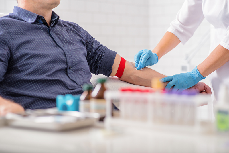627290560 Close up of nurse disinfecting male arm before blood test. Man is sitting on chair near medical set