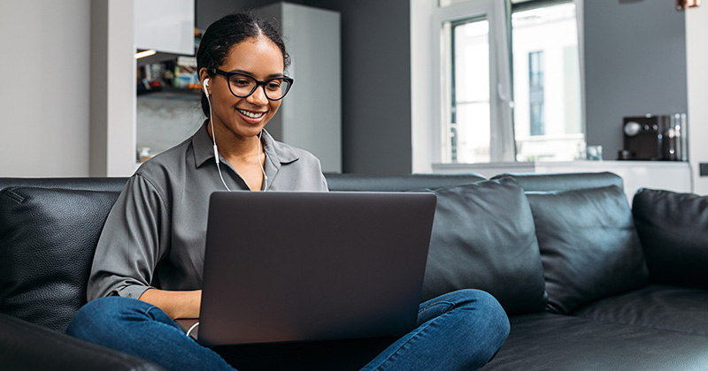 Woman sitting on couch working on laptop