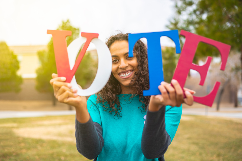 Holding VOTE letters colored in Red, White and Blue.