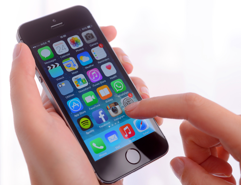 İstanbul, Turkey - January 24, 2014: Hands holding and touching iPhone 5s displaying home screen on a white background. The iPhone 5s is a touchscreen smartphone developed by Apple Inc.