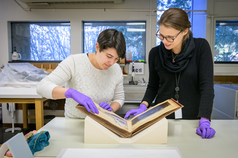 Master's students with the Winterthur / University of Delaware Program in Art Conservation (WUDPAC) program work on projects at the Winterthur Museum and Gardens; some collaborating with undergraduates and Ph.D. students from Art Conservation and Art History.

Pictured (from left): Jess Ortegon, a WUDPAC first-year fellow in library archives conservation education, and Jalena Jampolsky, a Ph.D. student in Art History, examining a photography album belonging to the St. Croix Landmarks Society Research Library & Archives.