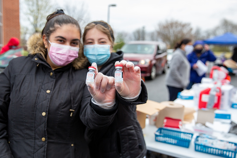 Senior UD nursing students assist with a drive-through COVID-19 vaccination event run by the Division of Developmental Disabilities Services and RiteAid. Pictured: senior nursing students Erika Sclafani (pink mask) and Erika Sclafani (blue mask)