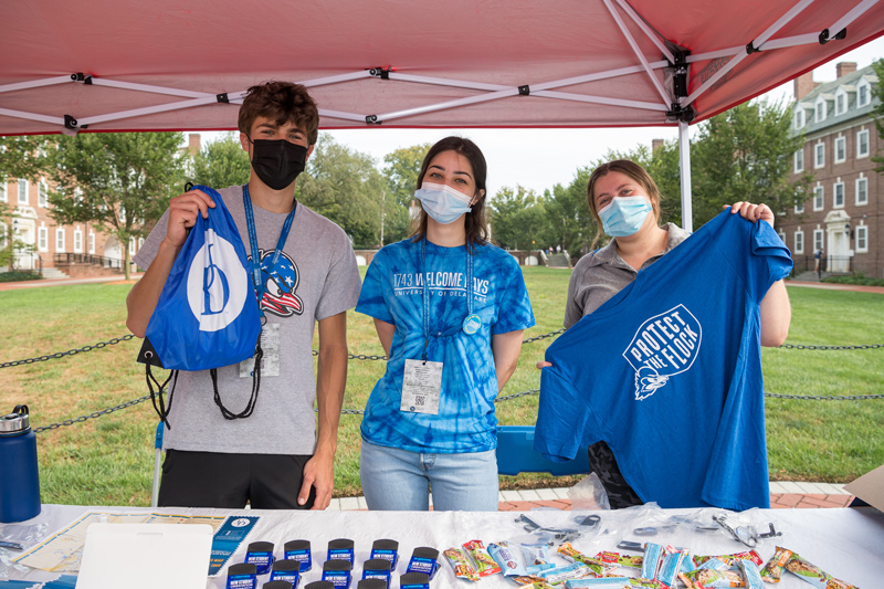 Students & faculty welcome back a new Fall 2021 semester as they hurry to classes for the start of classes. Tucker Smith '23 Engineering, Suzan Zien '23 CHS, and Kelsey Ladics from Student Life and a MS Health Promotion student all volunteer to help out at the Ask Me Tents on the North Green. 