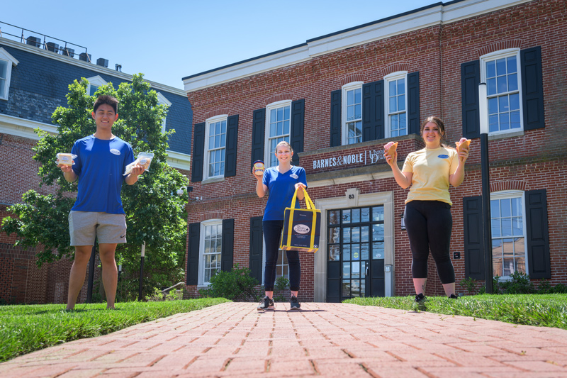 Nick Yang, Jazmin Reyes (yellow shirt), and Marina Hastings (blue shirt) all work with the UDairy Creamery, which will soon be taking over running the cafe in the UD Bookstore. Photographed outside the bookstore holding various UDairy items for a UDaily article announcing the grand opening of the new cafe in June, 2021 - just in time for New Student Orientation.