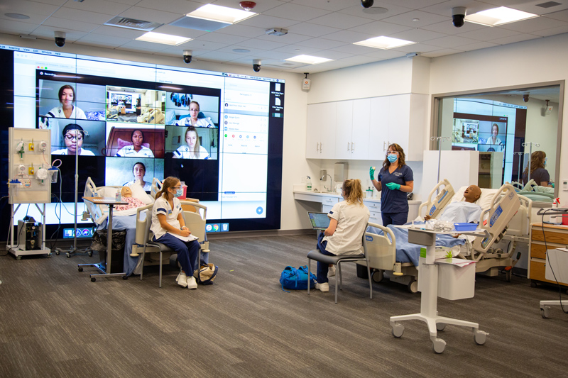 April Prior, simulation lab instructor, teaches half her nursing undergrad class live in the 4th floor sim lab in the Tower at STAR while the other half of her students watch live and participate over Zoom.