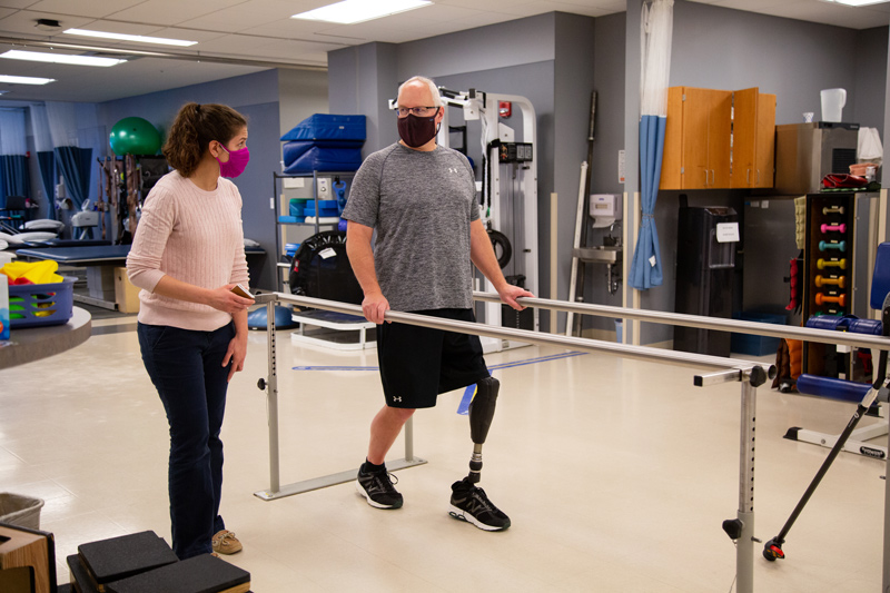 CHS-PT-Amputee-Glenn-Runyon-021121 Glenn Runyon works with Sarah Smith in the UD Physical Therapy Clinic. Glenn underwent osseointegration, which involves a metal rod being inserted into the a bone in place of wearing a socket. This is a fairly rare procedure - less than 200 of these type of surgeries in the U.S. Runyon is a history teacher and football coach for Concord High School.
Glenn also works with John Horne of Independence Prosthetics & Orthotics