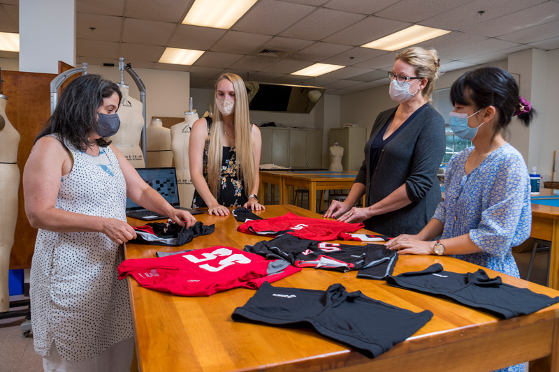 Pictured from left to right, Kelly Cobb, associate professor of fashion and apparel studies; Jenna Tomasch, a sophomore fashion design and product innovation major; Belinda Orzada, professor of fashion and apparel studies; and Jie Diao, visiting scholar, examine Tomasch’s high school volleyball uniform. As part of the Summer Scholars research program, Tomasch is utilizing direct observation, visual analysis and focus groups to understand performance wear needs for collegiate athletes.