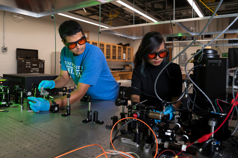 Aqiq Ishraq (left) and Nazifa Tasnim Arony align the laser for the scanning fluorescent confocal microscope in the University of Delaware’s Shared Optics Labs. The microscope is used to measure the emission of single photons from materials developed in the lab.