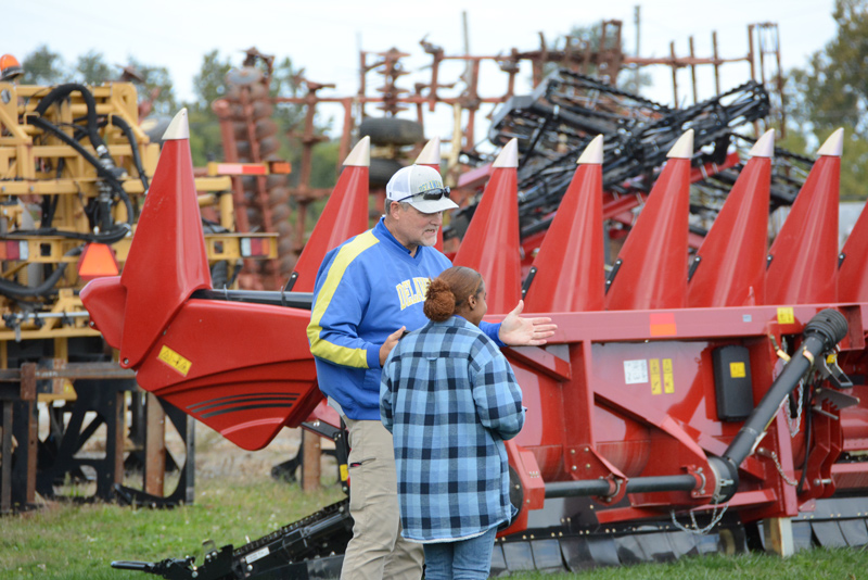 When it comes to farm equipment, expensive purchases don’t stop with a combine. UD Prof. Mark Isaacs explains to student Sydney Tankard the additional costs of each specialized crop “head” a farmer needs to purchase to go with the combine. The corn head seen in the background is roughly an additional $180,000. A grain table used to harvest soybeans and small grains is less expensive at about $150,000.