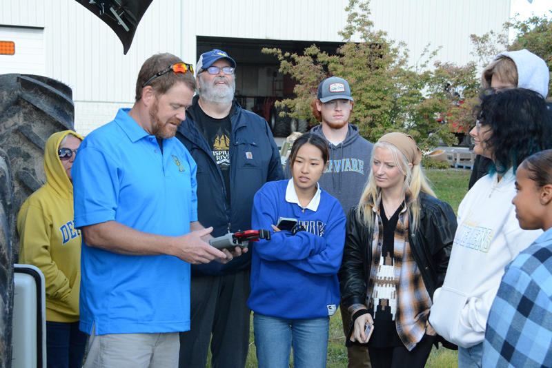 Hoober’s Dave Wharry flies a small drone explaining its field scouting benefits for farmers while UD students look on.