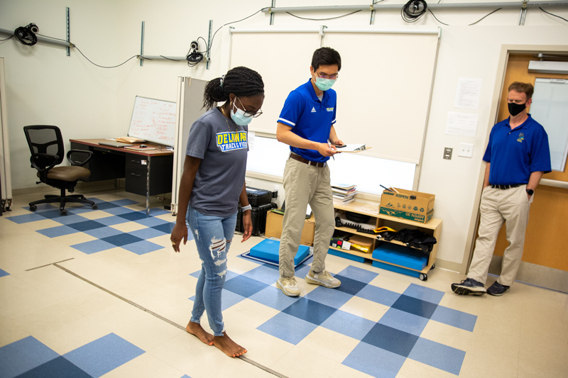 Joana Opung-Duah (left), a senior neuroscience and psychology major, runs through baseline concussion study protocol with Tsung-Yeh “Jacky” Chou, a doctoral student and certified athletic trainer from UD’s Athletic Training Research Lab. Chou is studying the effects of a concussion to neurological health in student athletes while Tom Buckley (right), an associate professor in the Department of Kinesiology and Applied Physiology, is studying prevention of future musculoskeletal injuries in athletes who’ve experienced concussion. This research is in partnership with UD Athletics.