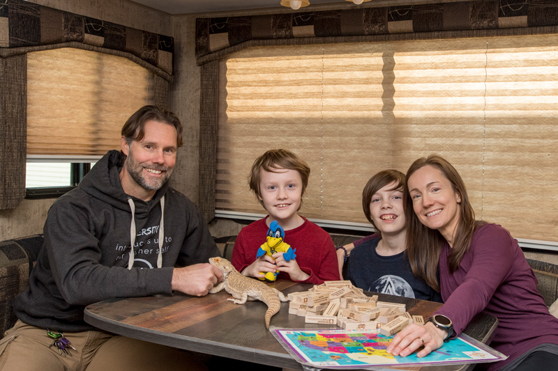 Family at dinette table in RV For their full-time cross-country adventure, the Willards packed only the most important possessions, including some family games, a pet bearded dragon named Max and — showcasing their University pride — a stuffed YouDee.