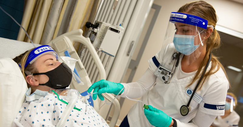 CHS-SON_Sim_Trach-030421 McDowell Hall’s newly renovated simulation space was in use during a class as nursing student Hannah Solon (right) practices taking care of tracheostomy patients. Healthcare Theatre Program Coordinator Heather Mekulski serves as the practice patient.