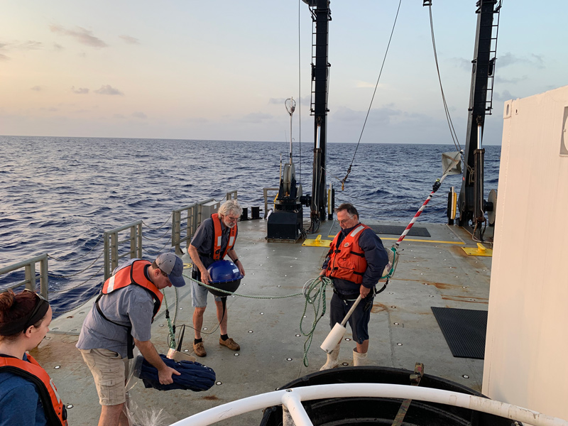 Members of the science party and R/V Sharp crew prepare to deploy the MetOcean Telematics drifter buoy, equipped with iridium satellite telemetry and GPS. The buoy allows the science team to follow and sample a single body of water for several days.