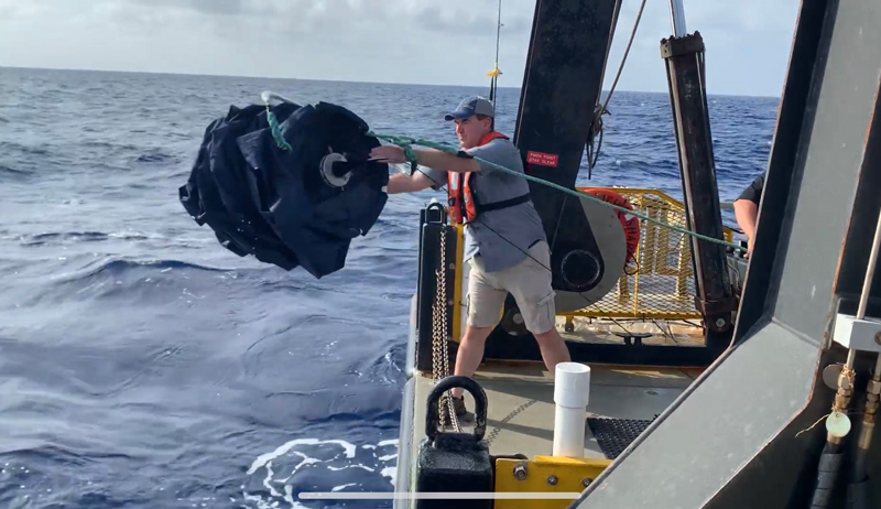 Co-Chief Scientist Shawn Polson releases the holey sock drogue, a type of sea anchor, that will drift 15 meters below the ocean surface. The science team followed the drogue for two experiments on either side of the Gulf Stream.