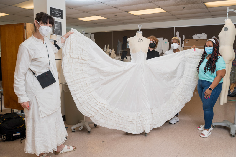 The team working on the gown demonstrates how voluminous the skirt is.