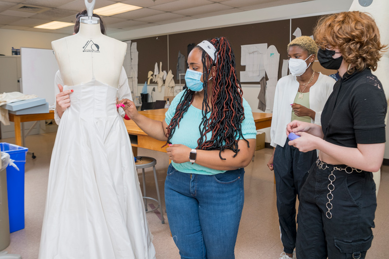 Students (from left) Kayla Brown, Maya Bordrick and Alex Culley study the way the gown will fall as Katya Roelse holds it on a mannequin in the Fashion and Apparel Studies workroom.