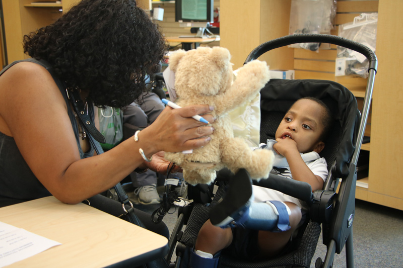 Quadia Ameen (left) encourages her son, Faheem, to interact with a teddy bear that plays peek-a-boo.