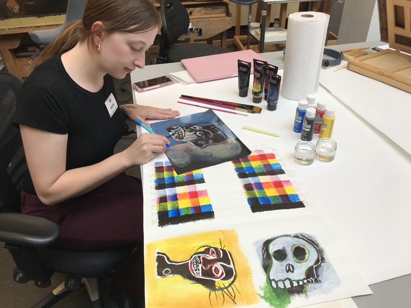 Kelsey Marino, a UD undergraduate alumna who helped create the toolkits for K-12 art classes, tries out the fluorescing materials and acrylic paint.