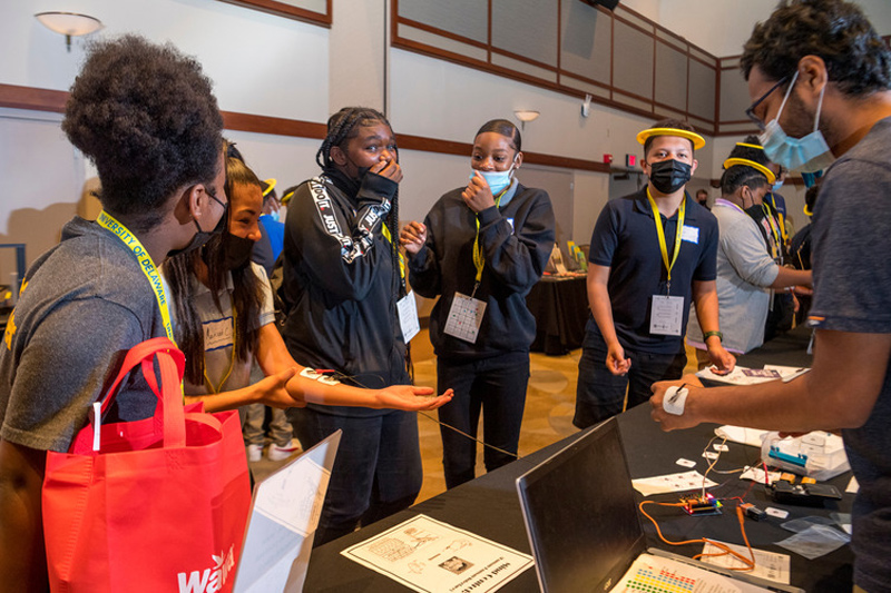 Students react when they see how doctoral student Devashish Pande can contract the muscles in his arm and, through connected electrodes, cause a visiting student’s fingers to twitch.