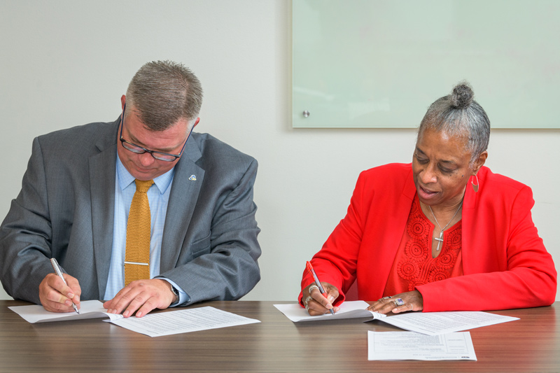 Director of University Archives and Records Management Ian Janssen and Denise R. Hayman sign the deed of gift for a donation of memorabilia from the Mu Pi chapter of Delta Sigma Theta, the first African American sorority at UD.