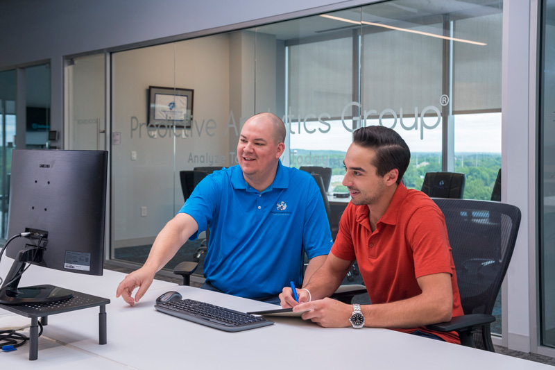 RSCH - Predictive Analytics Group - Carson Furci - 052422 David LaRoche (left), managing partner at Predictive Analytics Group and a University of Delaware alumnus, works with Carson Furci, who graduated with his degree in entrepreneurship from UD this past May. Furci did a student internship with the company and is now employed there full-time as a marketing/business analyst.