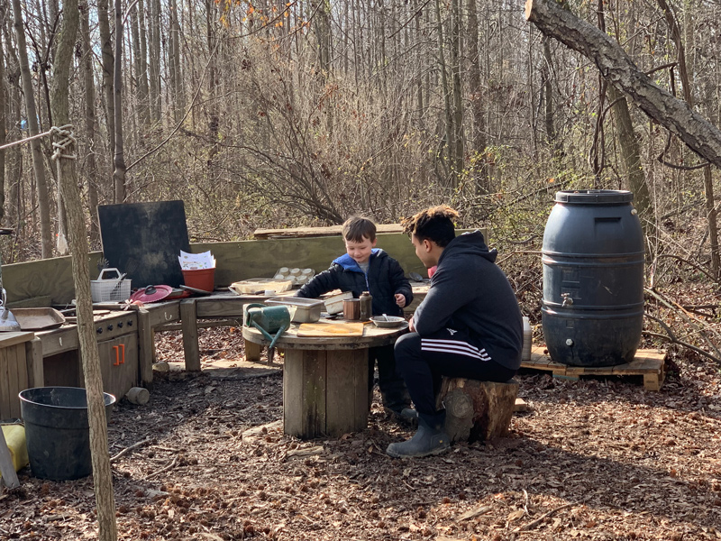 A UD student plays with a preschooler in the Lab School’s outdoor kitchen.
