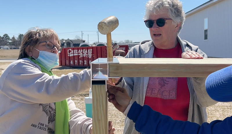 Masters of the Mallet volunteers Lynne Betts and Beth Kopicki assemble lumber to the metal corner frames.