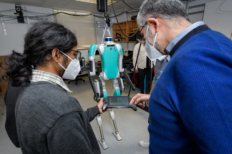 A team of UD engineers have been awarded about $800,000 from the National Science Foundation’s Major Research Instrumentation Program to develop a data-based approach to improving two-legged robots’ ability to walk on changing terrains. Here, mechanical engineering graduate student Abhijeet Kulkarni (left) and Mechanical Engineering Professor Ioannis Poulakakis (right) look at the controller for the high-tech robot named Digit. A team of UD engineers have been awarded about $800,000 from the National Science Foundation’s Major Research Instrumentation Program to develop a data-based approach to improving two-legged robots’ ability to walk on changing terrains. Here, mechanical engineering graduate student Abhijeet Kulkarni (left) and Mechanical Engineering Professor Ioannis Poulakakis (right) look at the controller for the high-tech robot named Digit.